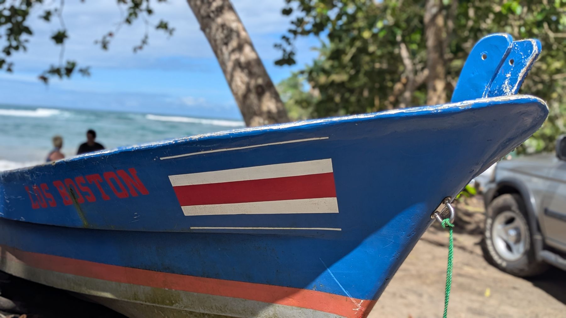 A blue fishing boat painted with the Costa Rican flag on the beach