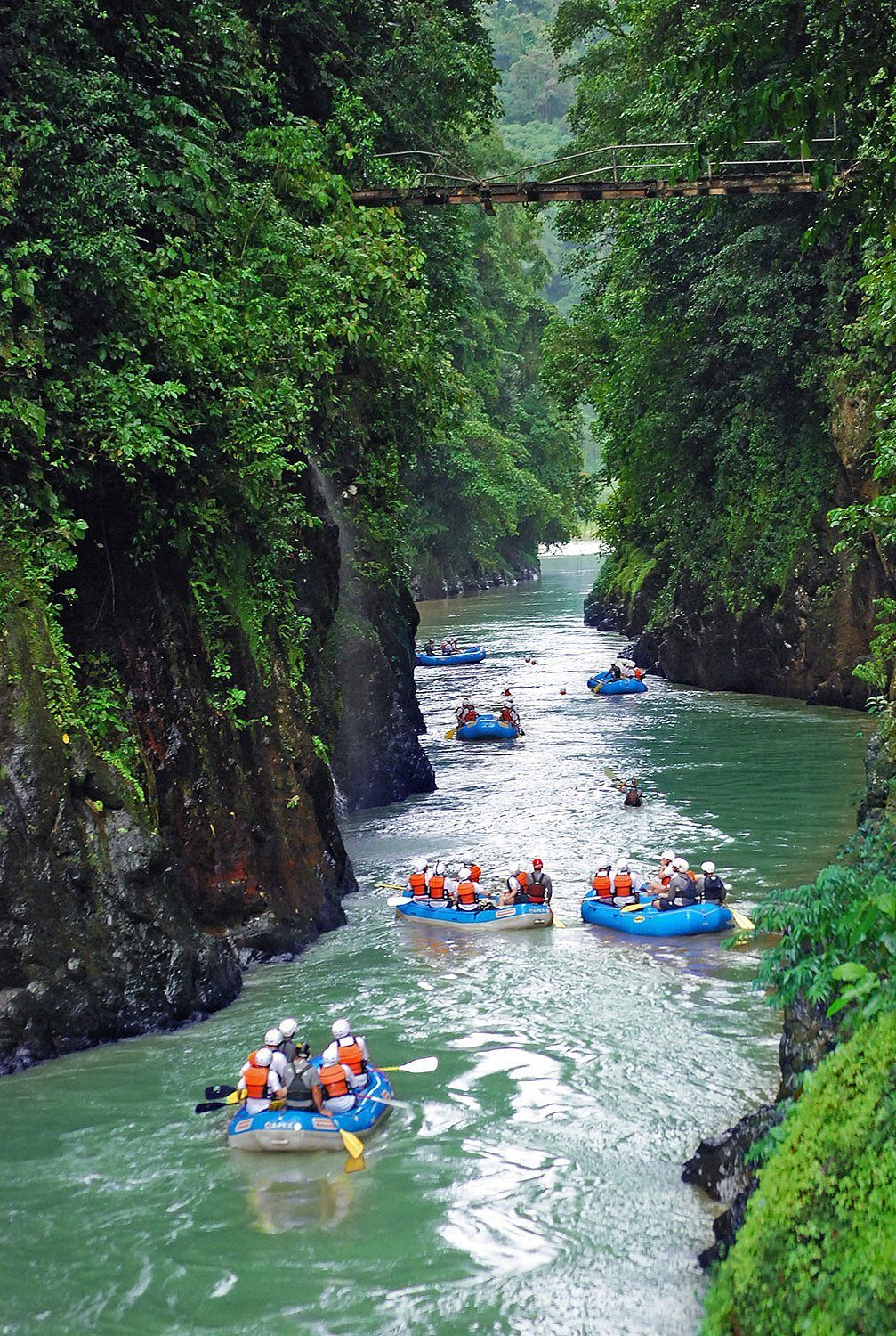 Rafts paddling through a green jungle canyon on the Pacuare River
