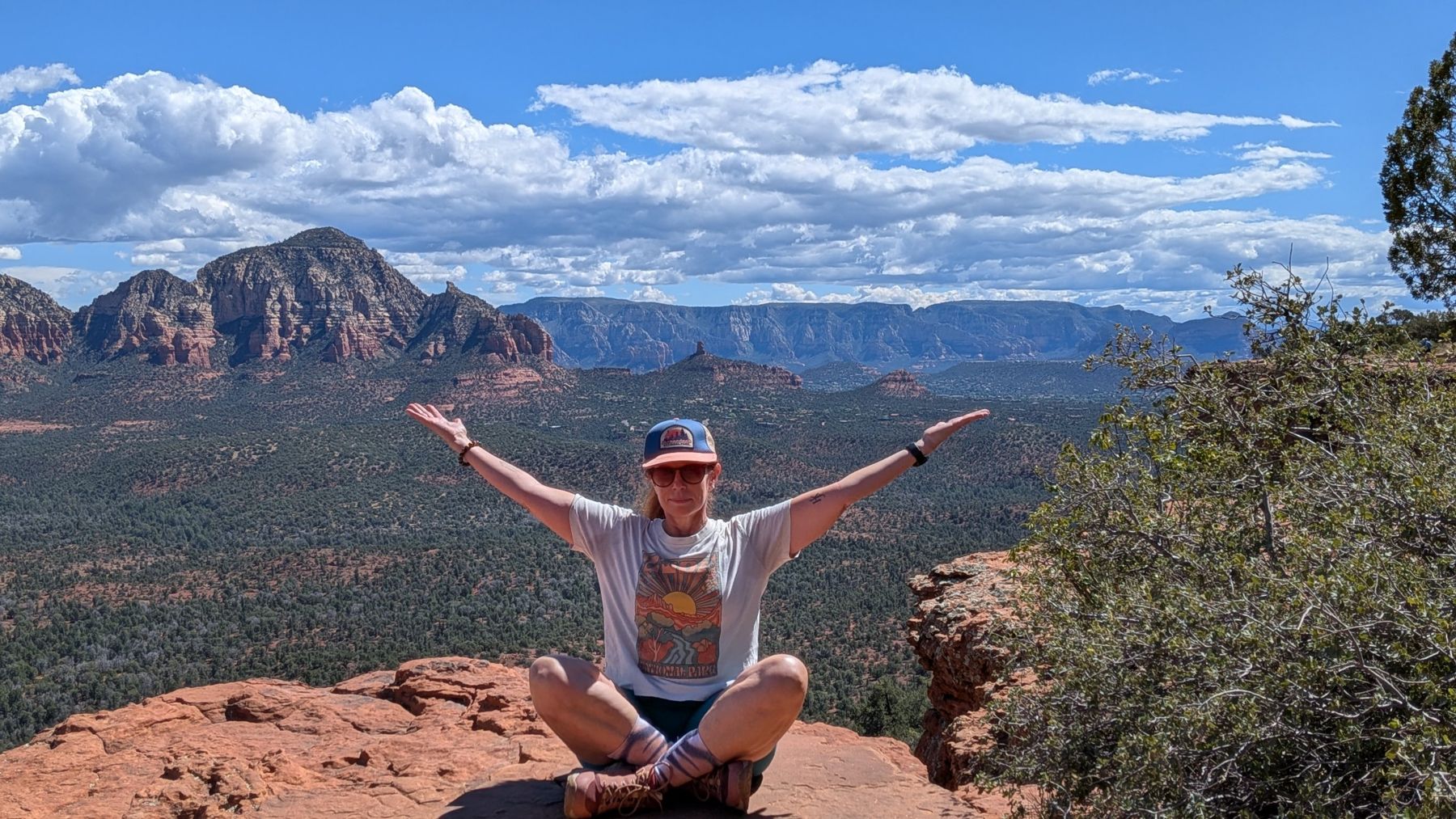 Marybeth with arms open wide on a red rock overlook