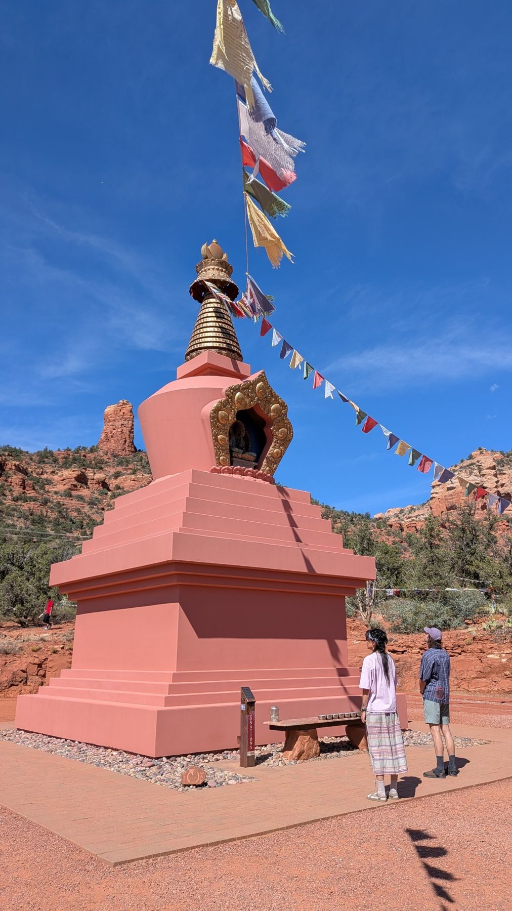 The Amitabha Stupa in Sedona with prayer flags against a blue sky